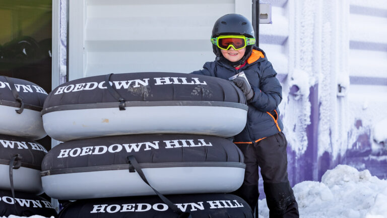 little boy standing near stack of snow tubes at Hoedown Hill