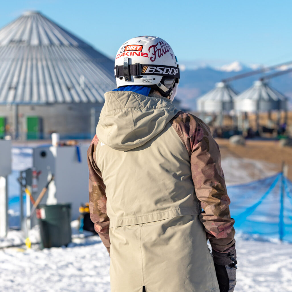 photo of snowboarder from behind with The Grainhouse in the background