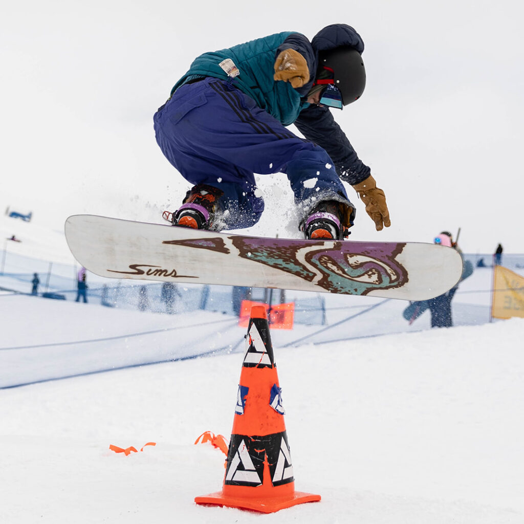 Snowboarder jumping over a cone